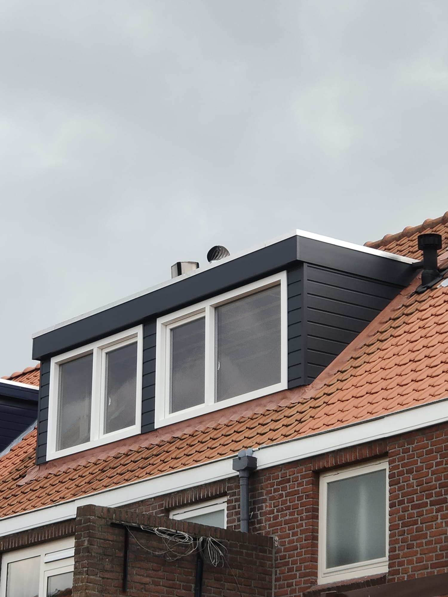 Dakkapel op een dak met oranje dakpannen