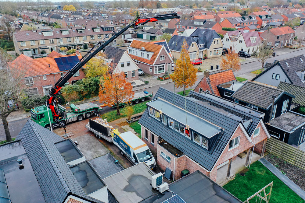 Een dakkapel van twaalf meter lang wordt op een dak gehesen.
