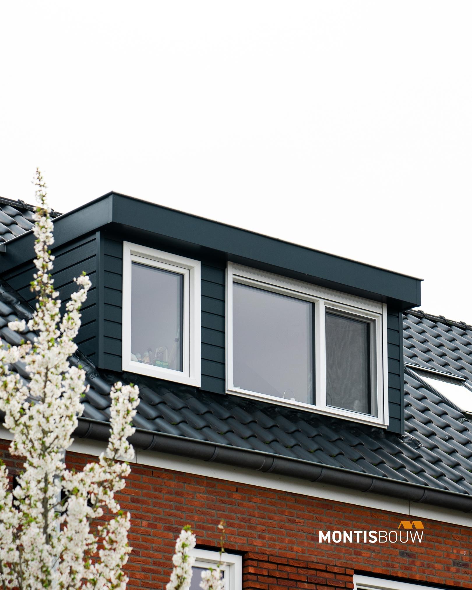 Dakkapel met donkergrijze bekleding en witte ramen op rode bakstenen woning