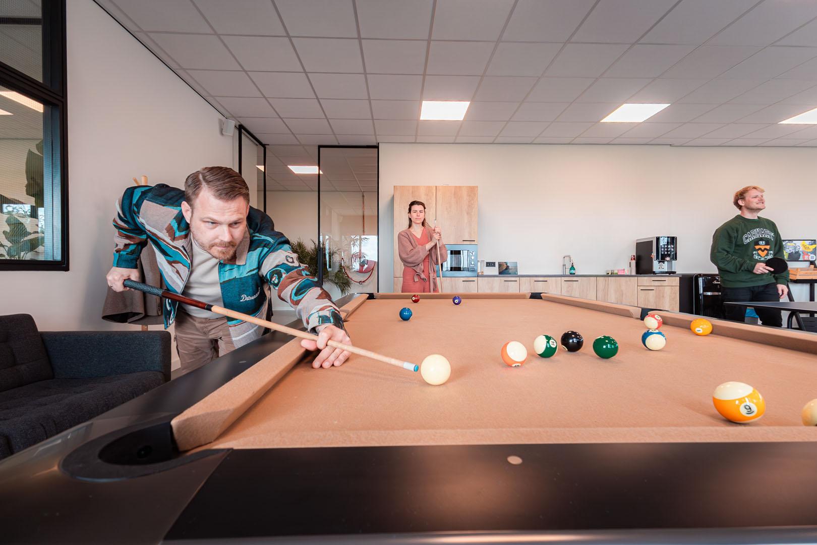 Werknemers spelen biljart en ontspannen in kantoorpauzeruimte