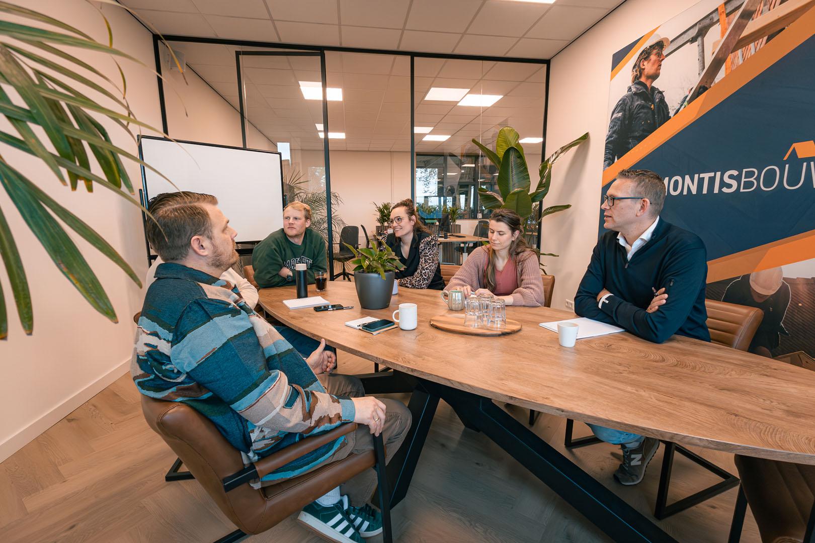 Team in vergadering aan tafel in modern kantoor met plantjes