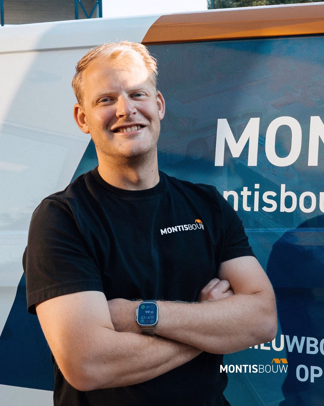 Lachende man in Montis Bouw-shirt met armen over elkaar