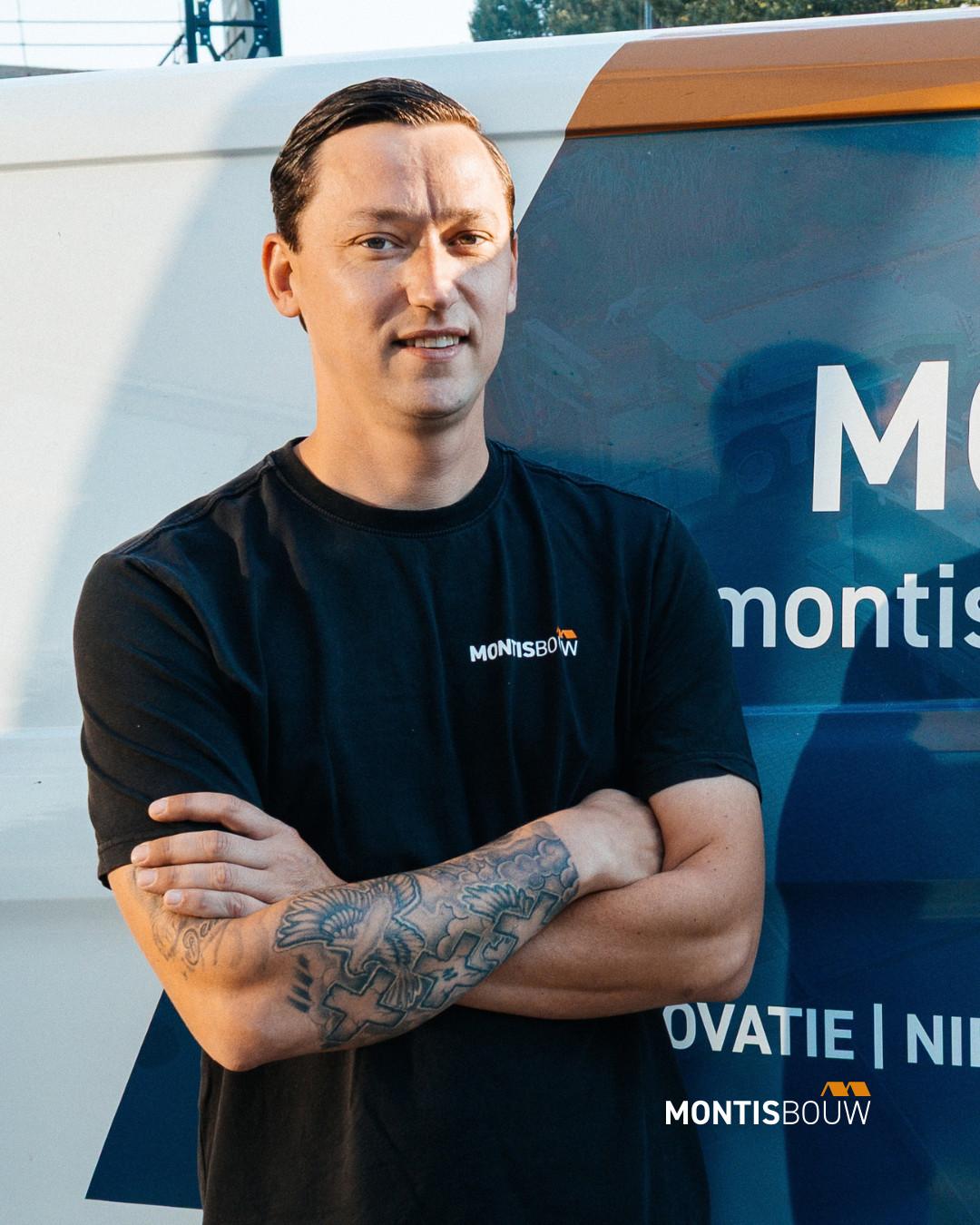 Man in MONTIS BOUW shirt met armen over elkaar voor bouwequipment