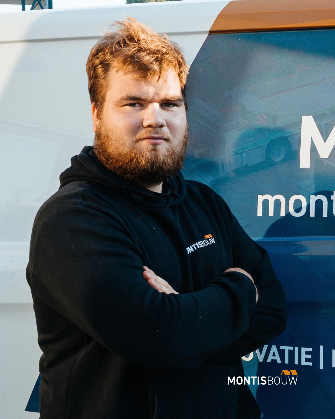 Man in MONTISBOUW-hoodie met gekruiste armen voor bedrijfsvoertuig