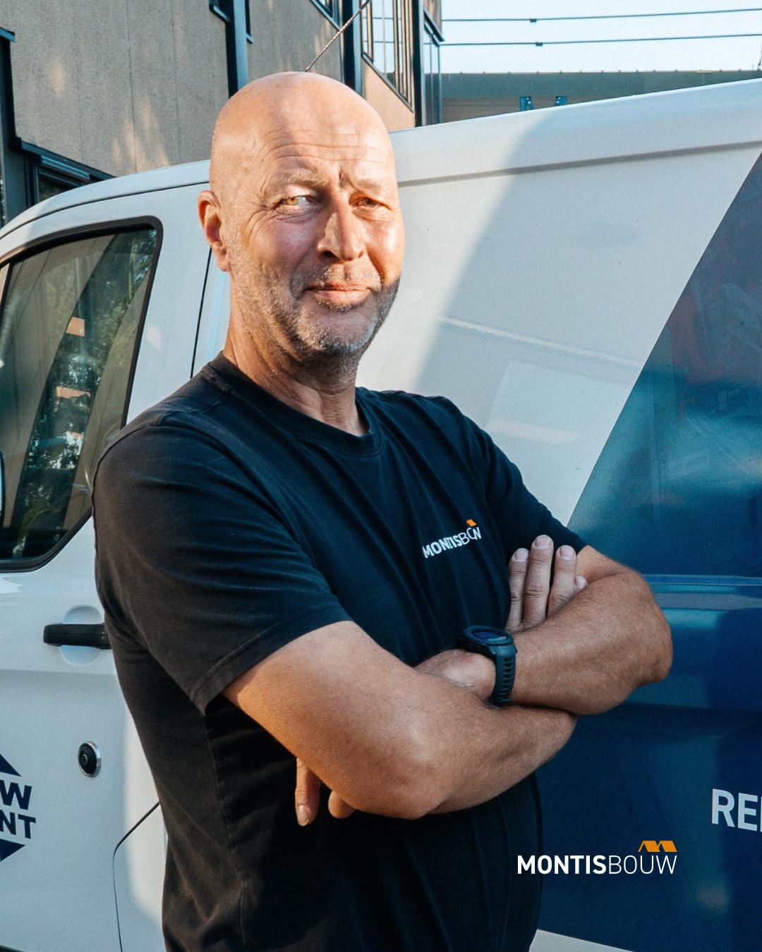 Man met armen over elkaar voor witte bestelwagen, Montis Bouw shirt